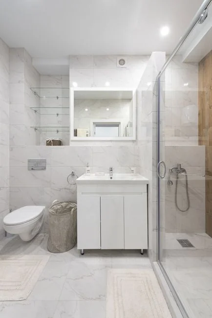 A cleaner dressed in protective coveralls and gloves vacuums a contemporary living room.